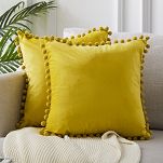 Żółte poduszki dekoracyjne z pomponami
