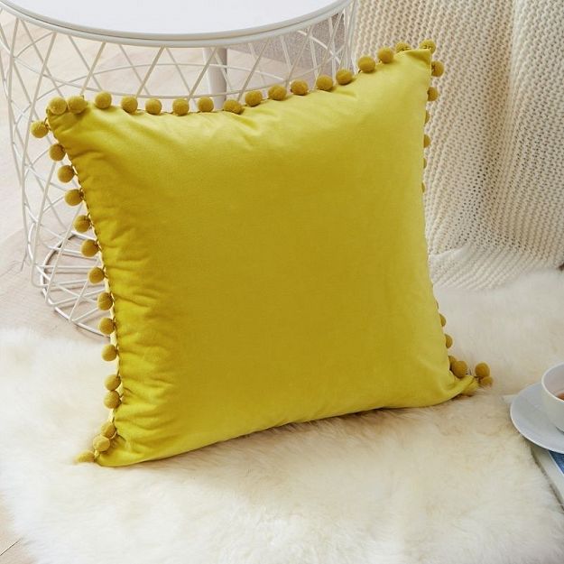 Żółta poduszka dekoracyjna z pomponami aksamit syntetyczny
